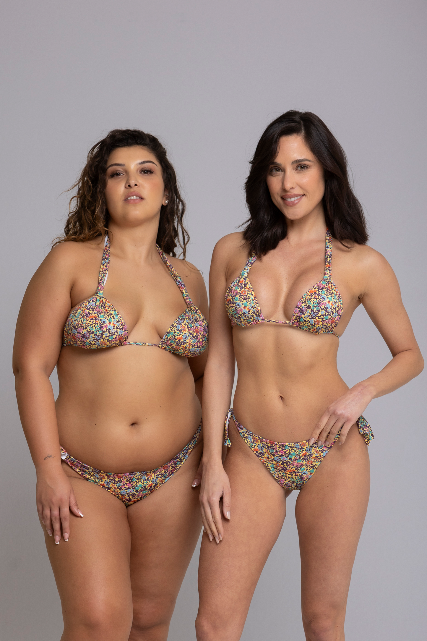 Two models wearing Megan Floral Yellow Triangle Bikini Set front view - one in size small, one in size large